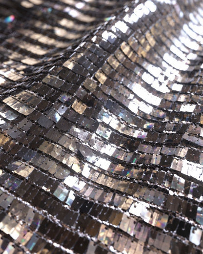 Close-up of FlexyDrip silver sequin skirt showing textured surface with reflective metallic tiles.
