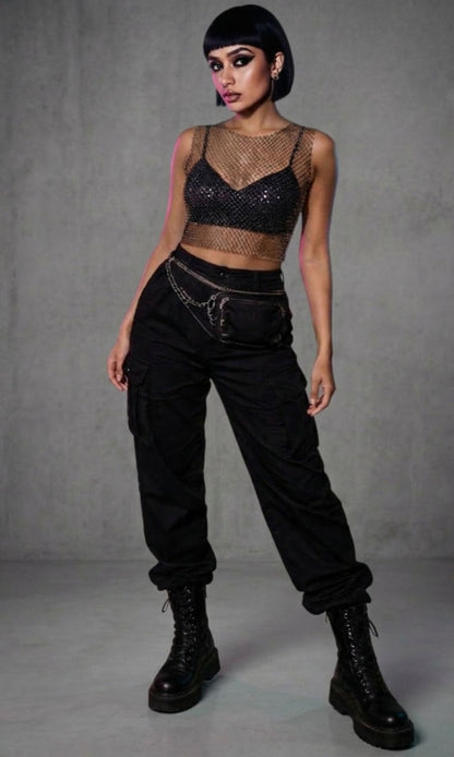 Woman wearing FlexyDrip  black rhinestone mesh top and black pants with a gray background