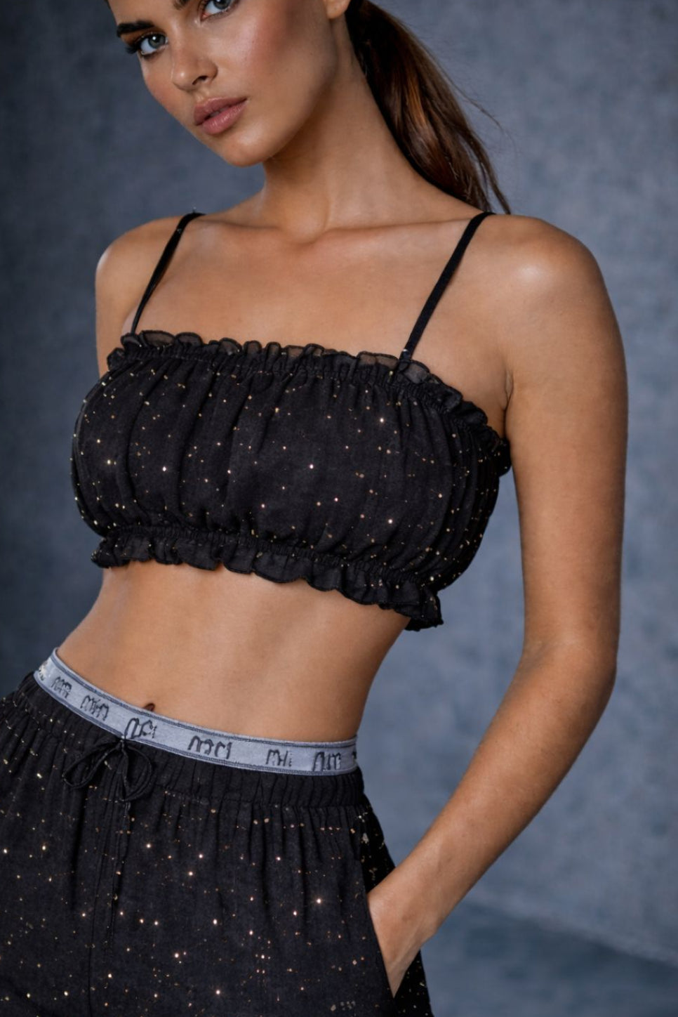 Woman wearing Flexydrip black rhinestone top and pants against a gray background