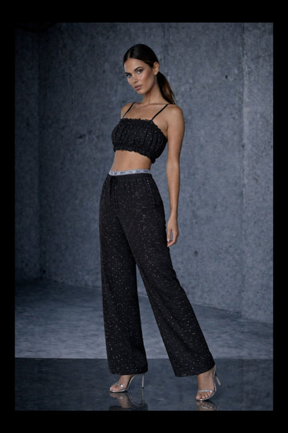 Woman wearing a Flexydrip black rhinestone outfit against a gray background